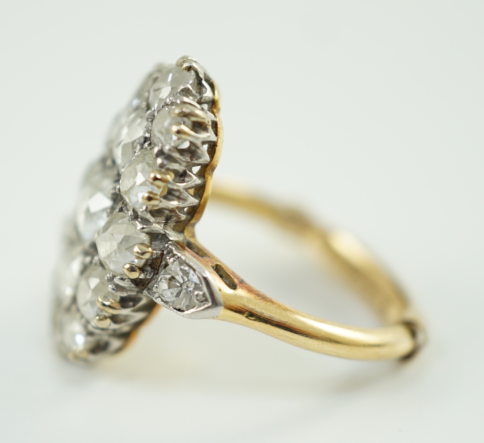 An 18ct gold and oval diamond cluster dress ring, with diamond set shoulders